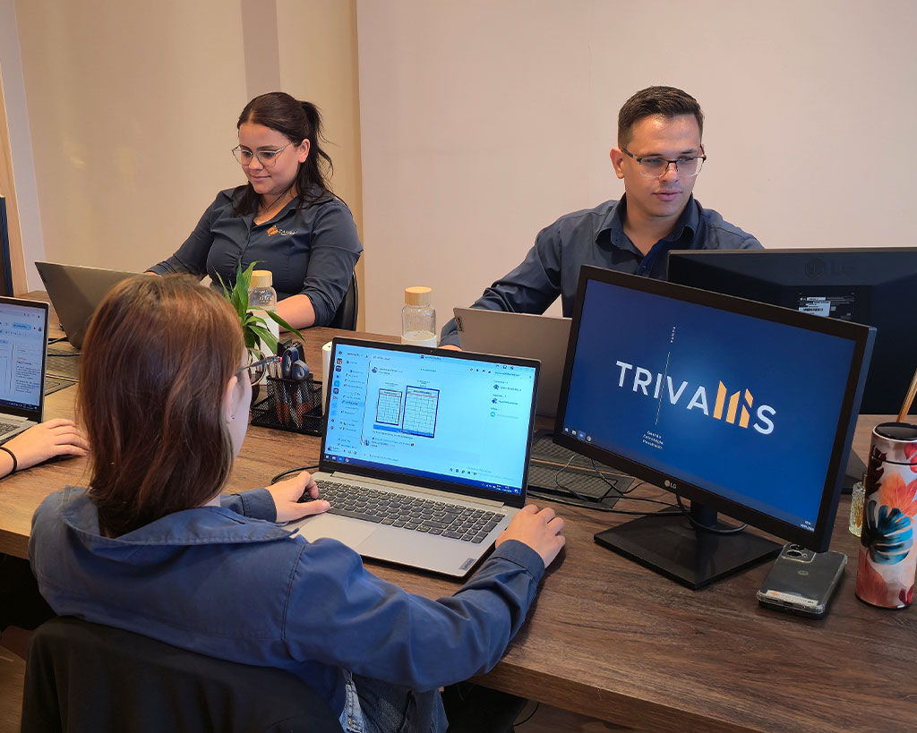 Equipe da Trivallis Contabilidade trabalhando em uma mesa de madeira com notebooks.